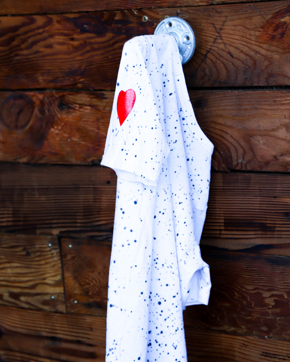 White splatter hand dyed tie dye t-shirt with red heart on wood wall