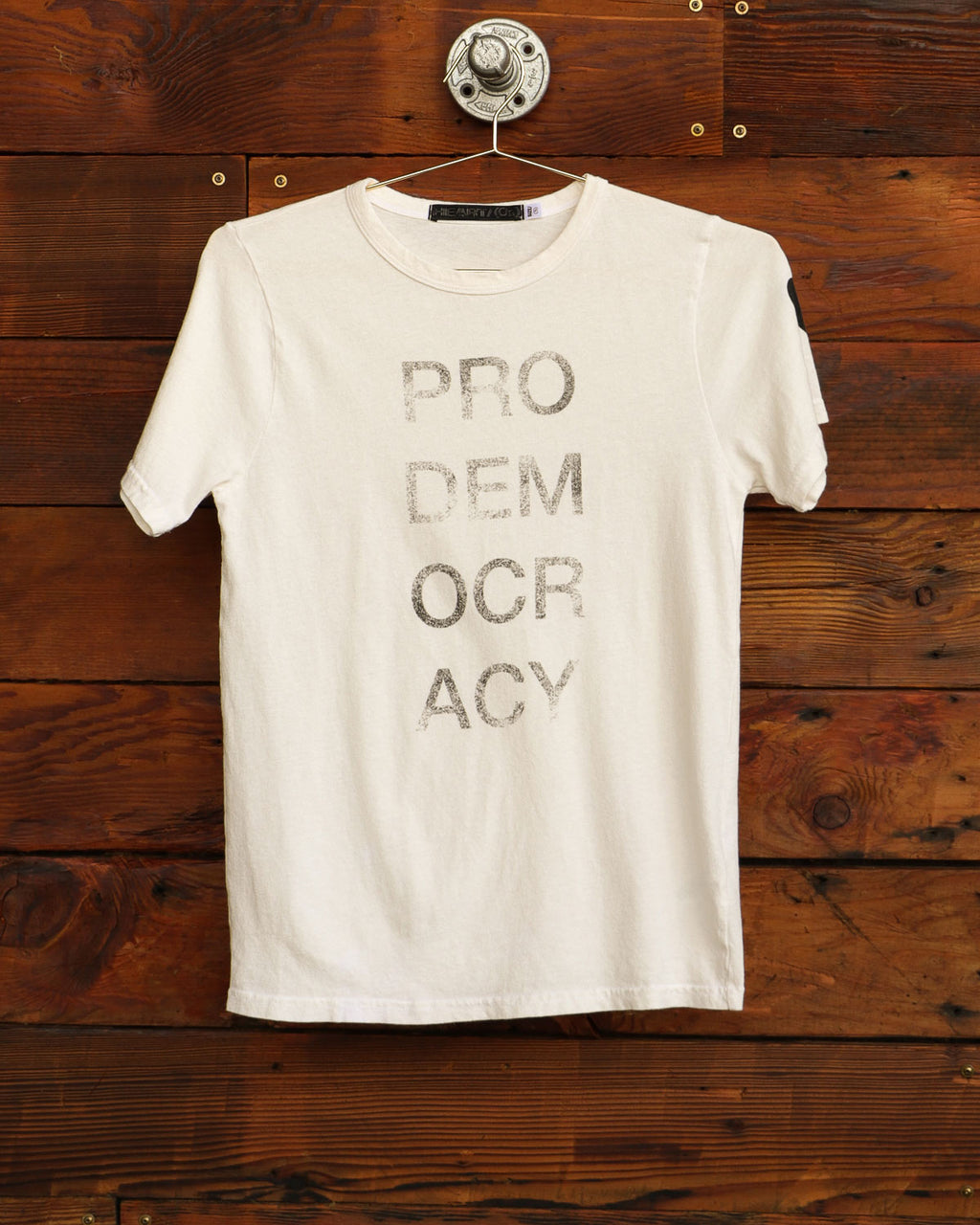 Pro democracy graphic tee in vintage white hanging on wood wall