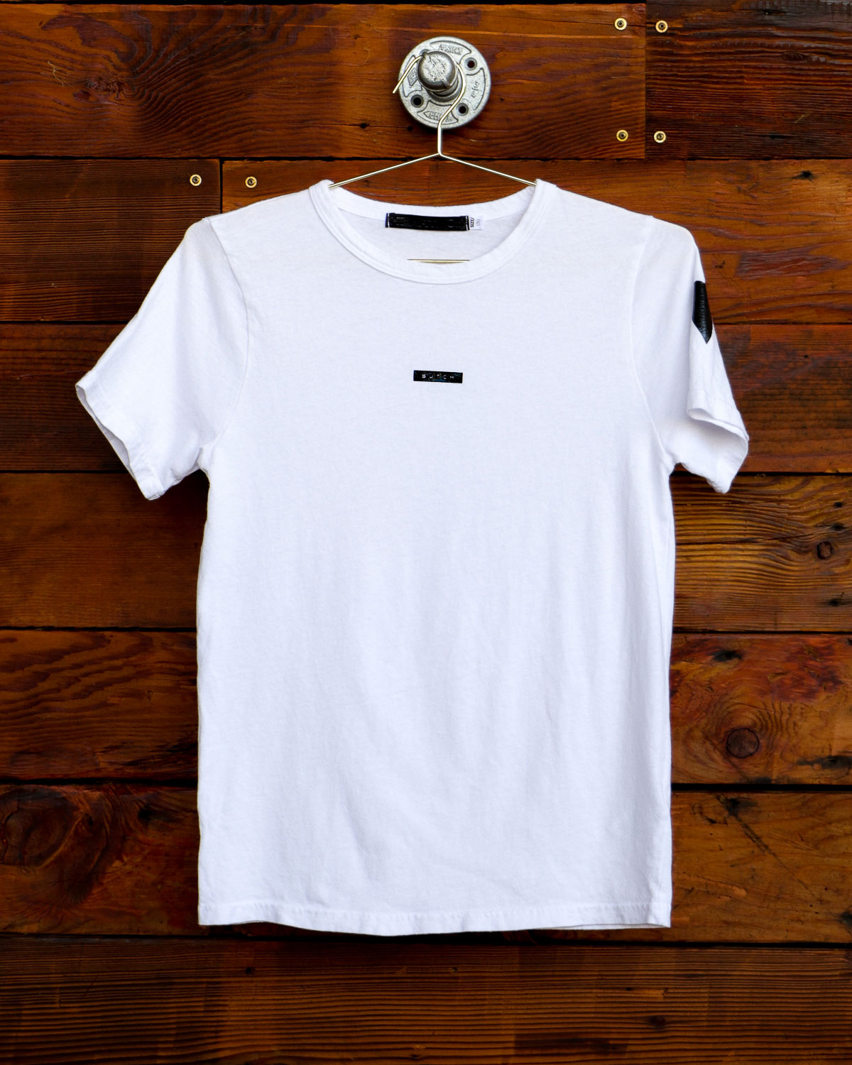 White Butch label t-shirt hanging on weathered wood wall