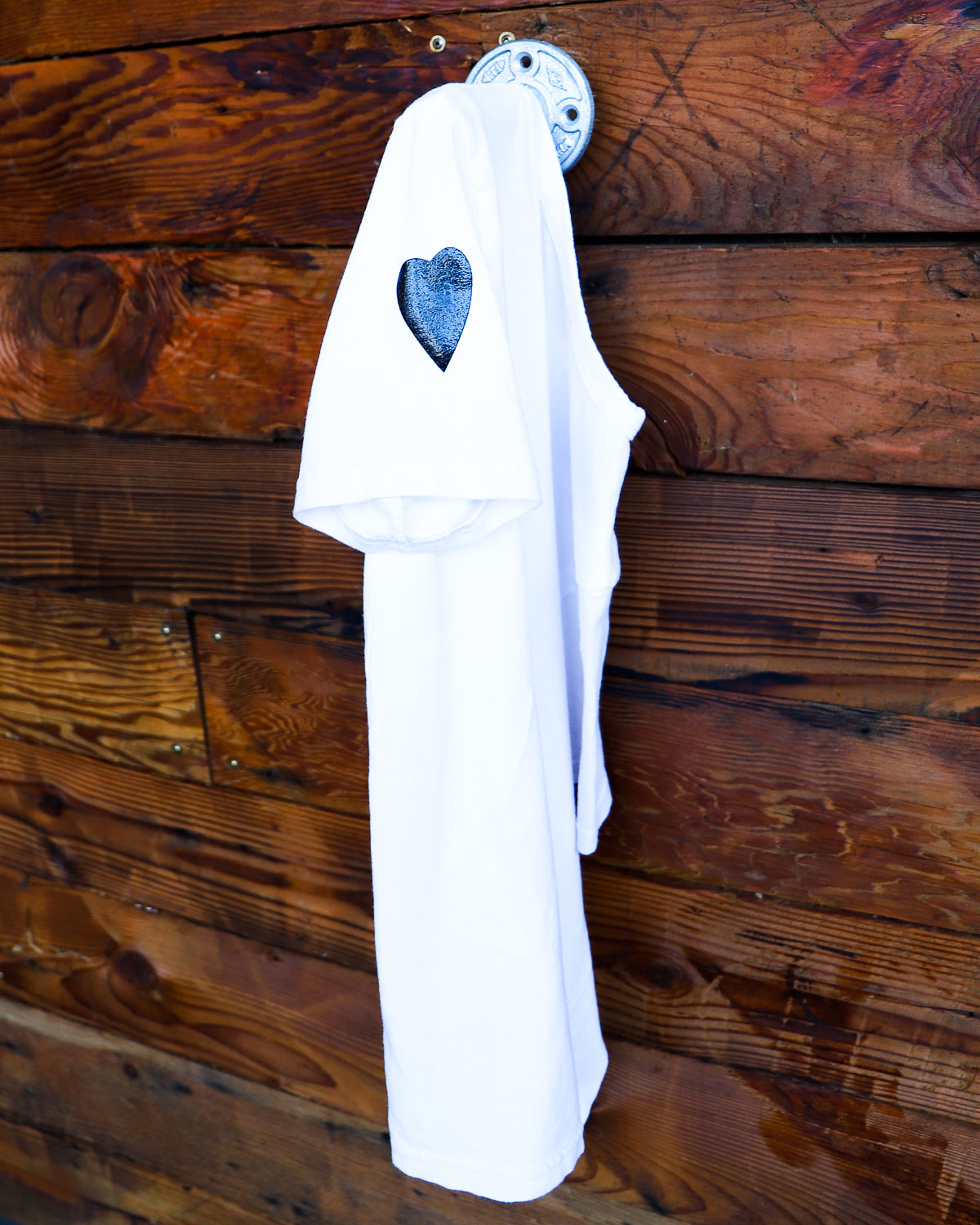 White Sissy label t-shirt hanging on weathered wood wall