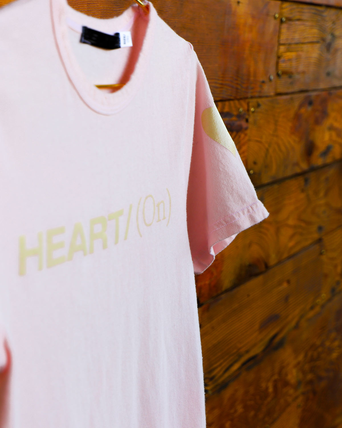 Light pink Heart On logo t-shirt hanging on wood wall