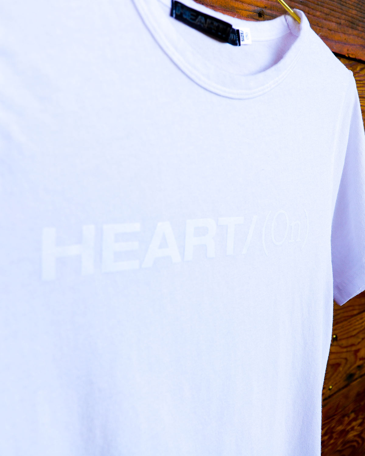 Close up of White Heart On logo t-shirt hanging on wood wall