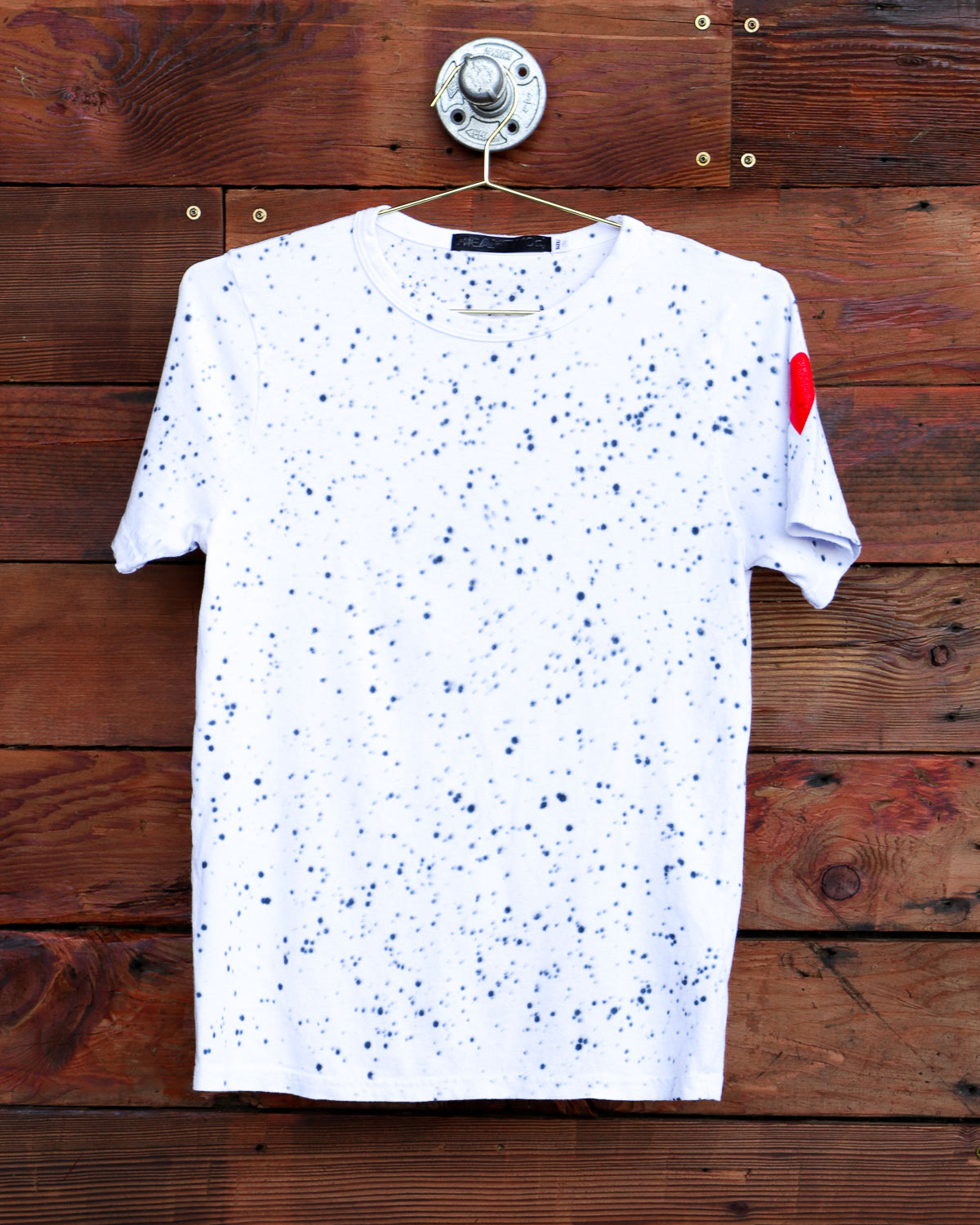 White splatter hand dyed tie dye t-shirt hanging on wood wall