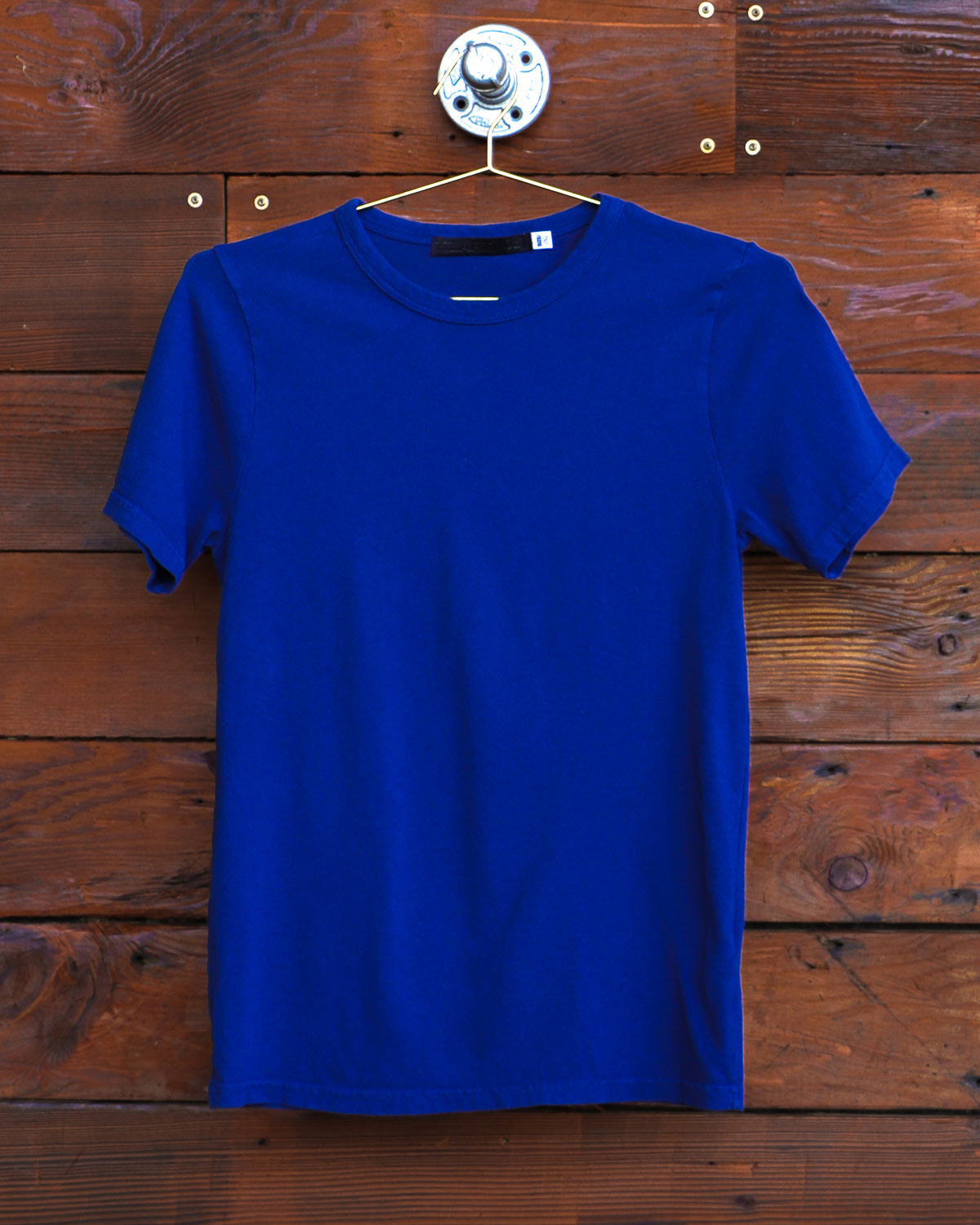 Blue Heart On logo t-shirt hanging on wood wall