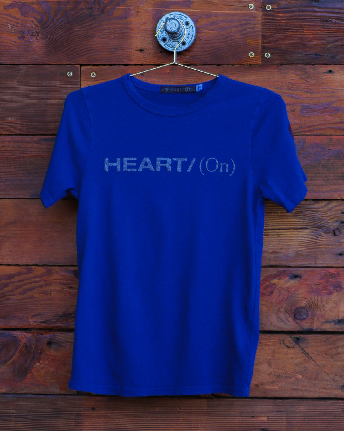 Blue Heart On logo t-shirt hanging on wood wall