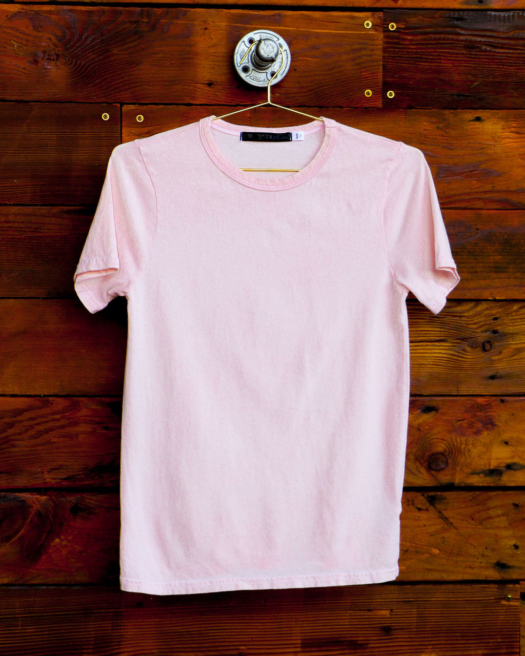 Light pink t-shirt hanging on wood wall