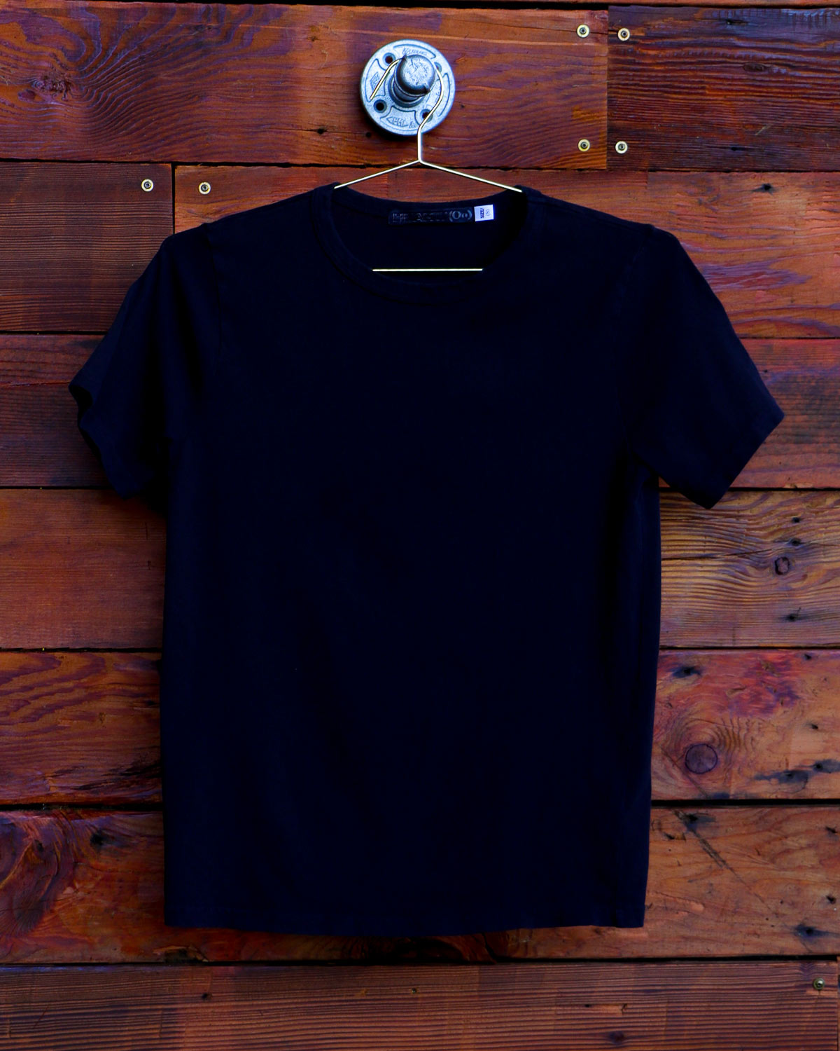 Black t-shirt hanging on wood wall