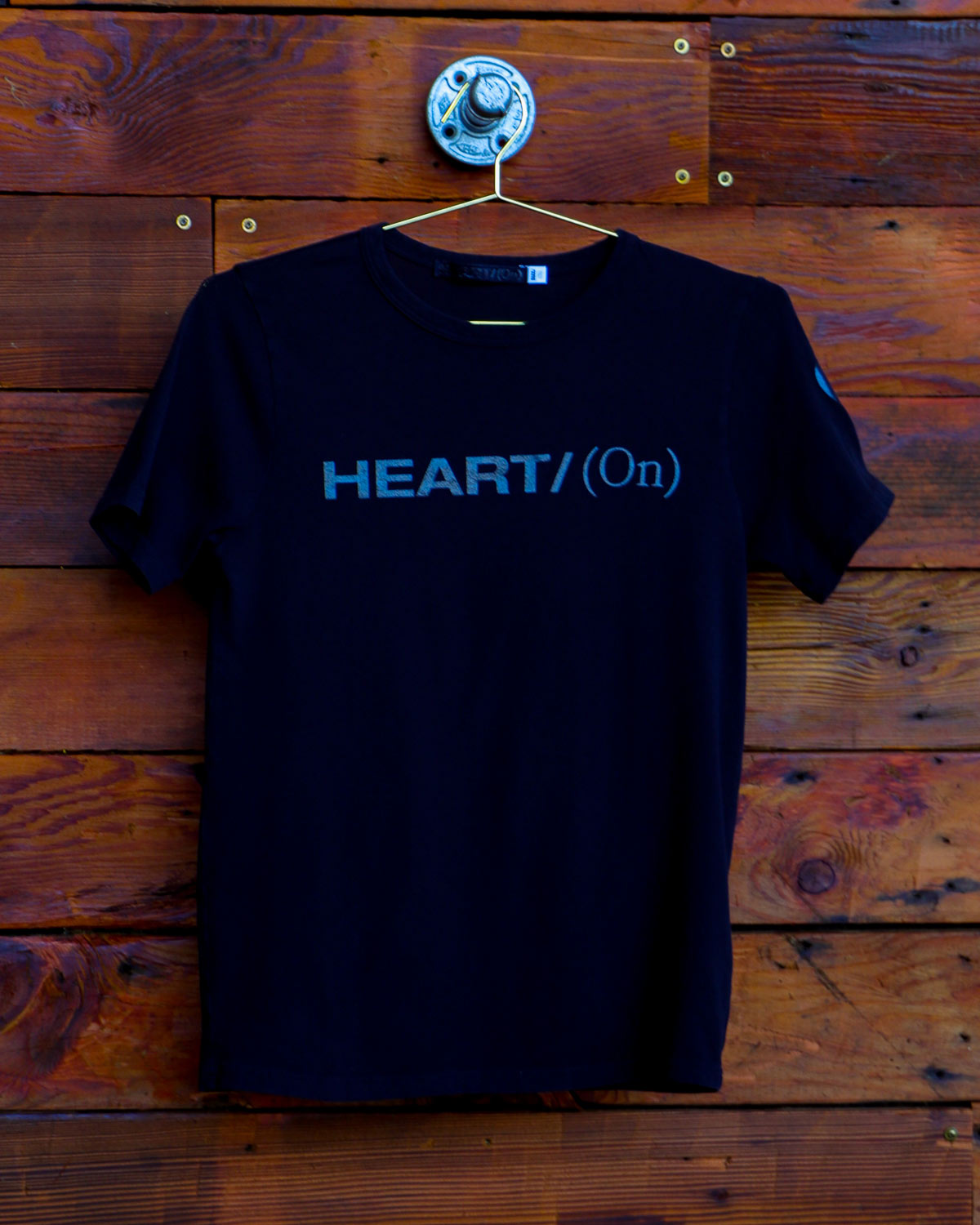 Black Heart On logo t-shirt hanging on wood wall