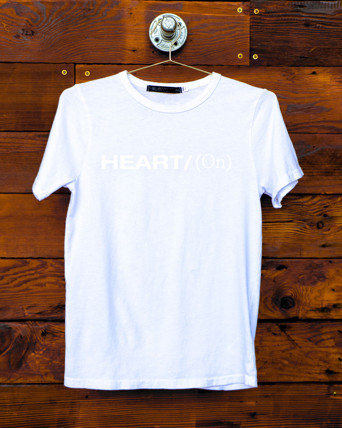 White Heart On logo t-shirt hanging on wood wall