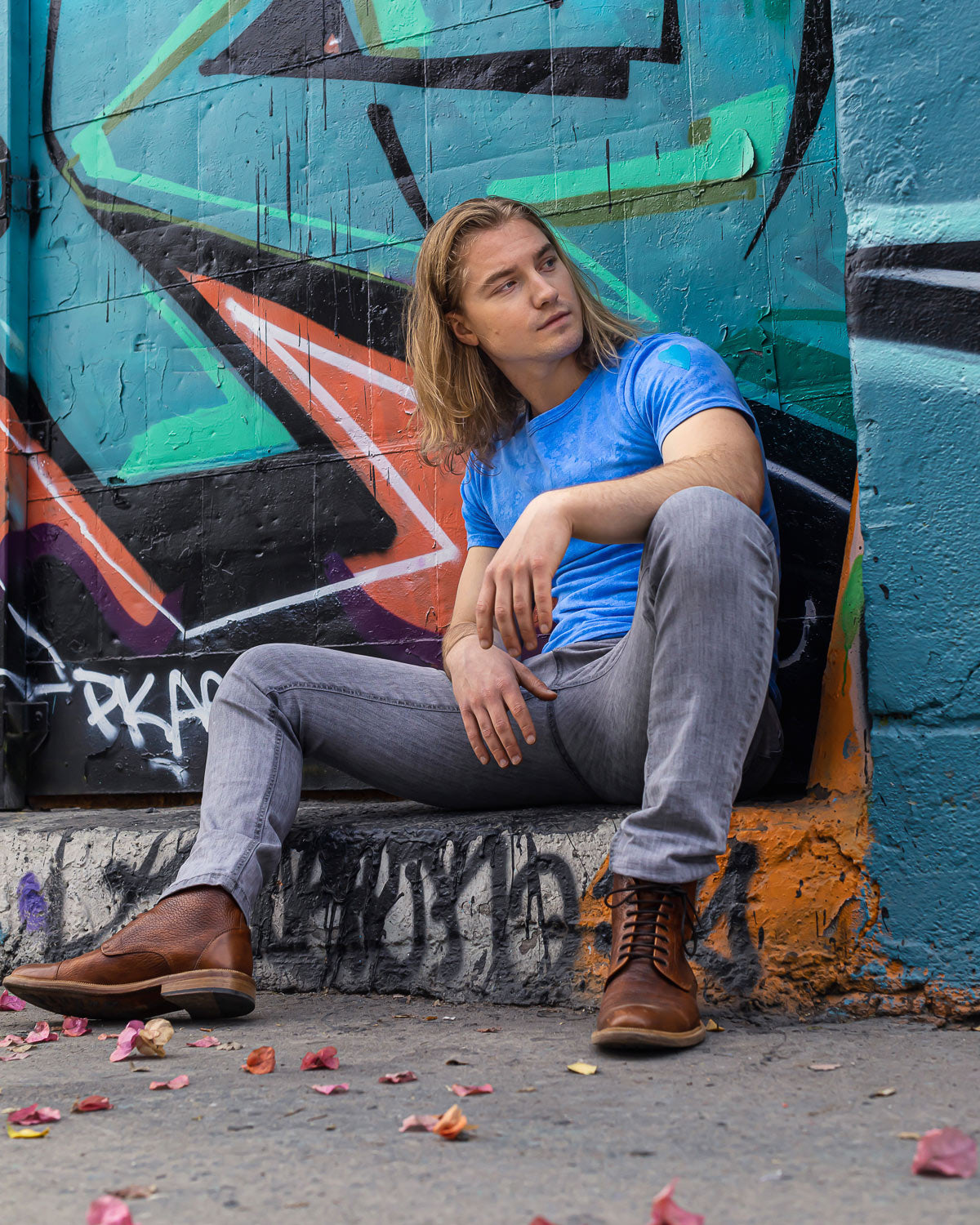 Model wearing Blue hand dyed cloud tie dye t-shirt on a hanger in front of graffiti