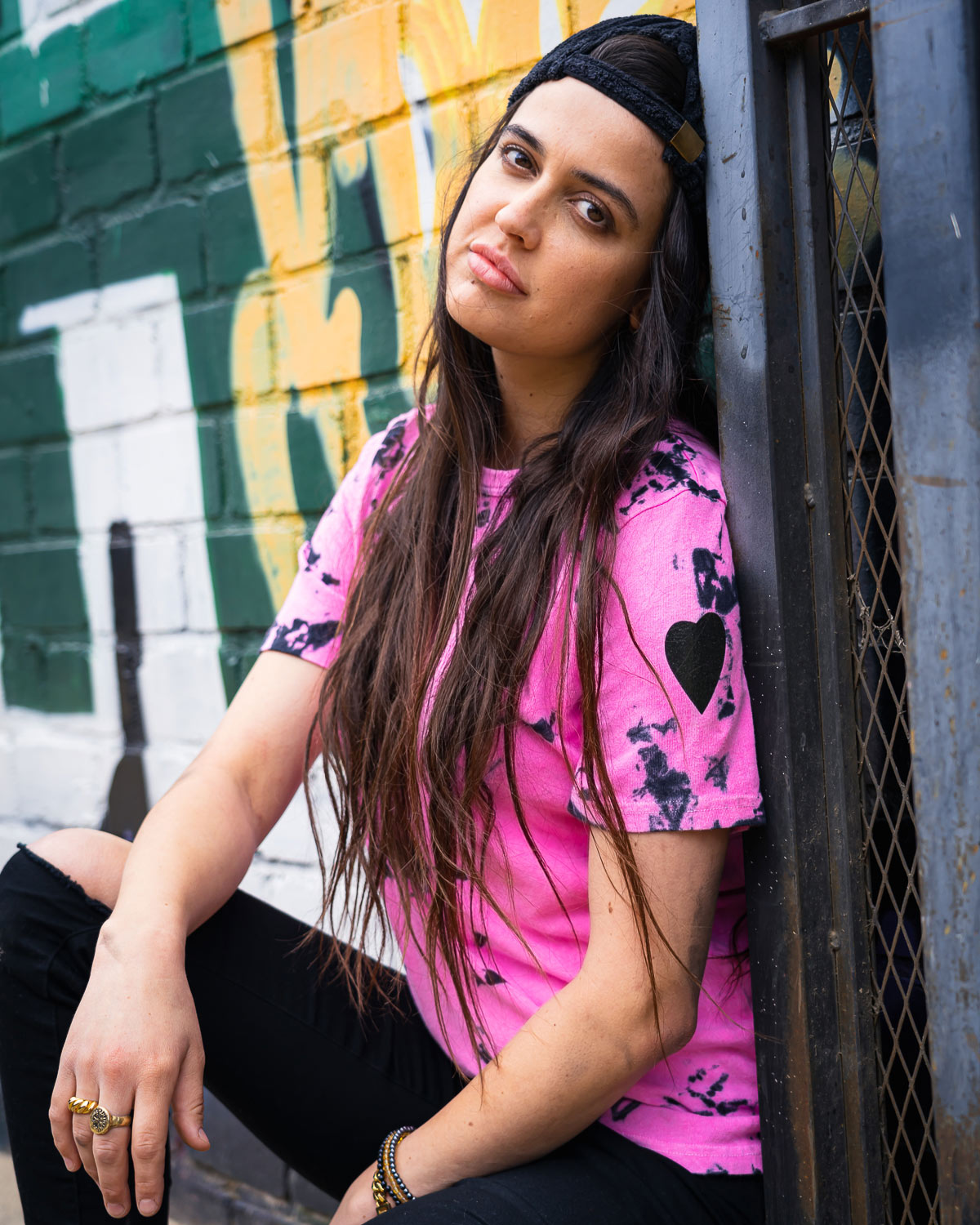 Model wearing pink and black hand dyed tie dye t-shirt against graffiti wall